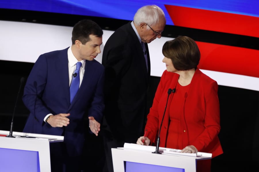 Democratic presidential candidates former South Bend Mayor Pete Buttigieg, left, and Sen. Amy Klobuchar, D-Minn., talk while Sen. Bernie Sanders, I-Vt., heads off stage at a break Tuesday, Jan. 14, 2020, during a Democratic presidential primary debate hosted by CNN and the Des Moines Register in Des Moines, Iowa.