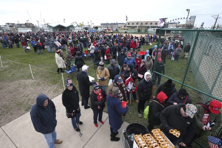People stand in the cold in a field, as they line up to enter the Wildwoods Convention Center for a campaign rally with President Donald Trump, Tuesday, Jan. 28, 2020, in Wildwood, N.J.