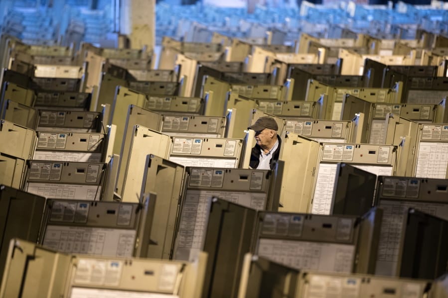 FILE- In this Oct. 14, 2016, file photo, a technician works to prepare voting machines to be used in the presidential election, in Philadelphia. The FBI, in a change of policy, is committing to inform state officials if local election systems have been breached, federal officials told The Associated Press.