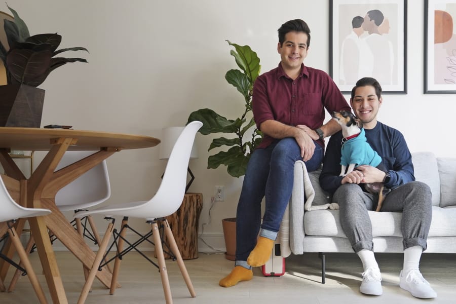In this Monday, Nov. 25, 2019 photo, Zachariah Mohammed, left, Pete Mancilla, and their dog Remy pose for a picture in their apartment in New York. Most of the furniture in their apartment, including the couch, the table and chairs, the side table and the bar cart, are rented. Furniture-rental startups and other companies are aiming to rent furniture to millennials who don&#039;t want to commit to big purchases or move heavy furniture and are willing to pay for the convenience.