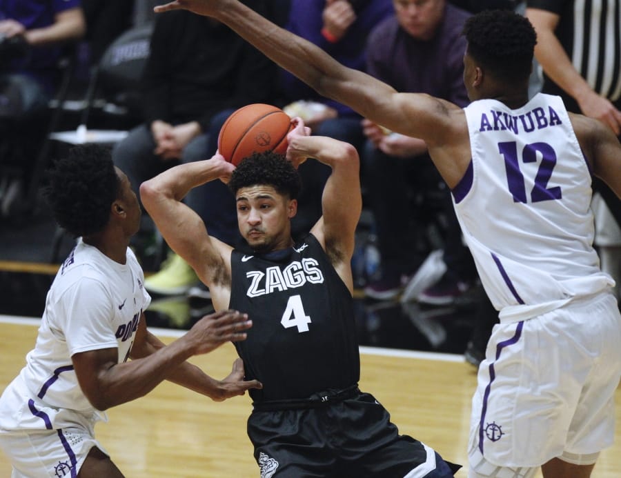 Portland guard Quincy Ferebee, left, and center Theo Akwuba, right, defend against Gonzaga guard Ryan Woolridge, center, during the first half of an NCAA college basketball game in Portland, Ore., Thursday, Jan. 2, 2020.