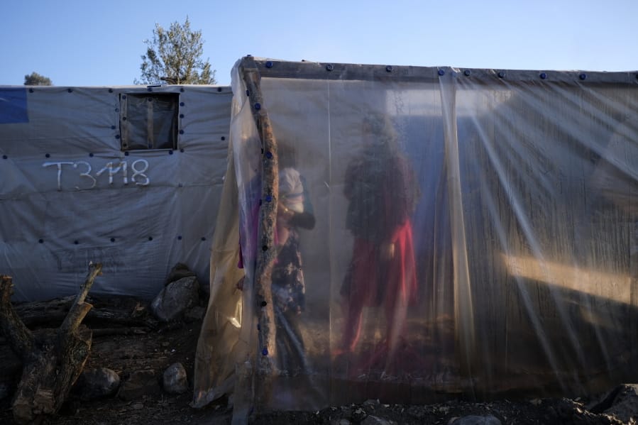 Migrants stand next to tents outside the Moria refugee camp on the northeastern Aegean island of Lesbos, Greece, on Wednesday, Jan. 22, 2020. Some businesses and public services on the eastern Aegean island are holding a 24-hour strike on Wednesday to protest the migration situation, with thousands of migrants and refugees are stranded in overcrowded camps in increasingly precarious conditions.