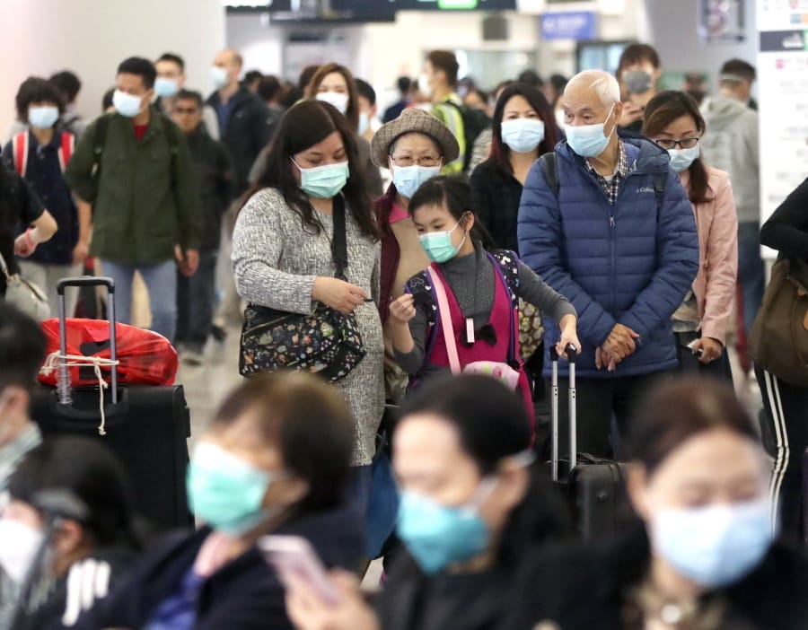 Passengers wearing protective face masks enter the departure hall of a high speed train station in Hong Kong, Friday, Jan. 24, 2020.