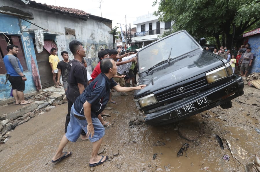 Residents move the wreckage of cars that were swept away by flood in Bekasi, West Java, Indonesia, Friday, Jan. 3, 2020.Severe flooding in greater Jakarta has killed scores of people and displaced tens of thousands others, the country&#039;s disaster management agency said.