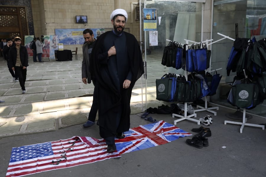 A cleric walks on the U.S. and British flags while leaving a gathering to commemorate the late Iranian Gen. Qassem Soleimani, who was killed in Iraq in a U.S. drone attack on Jan. 3, and victims of the Ukrainian plane that was mistakenly downed by the Revolutionary Guard last Wednesday, at the Tehran University campus in Tehran, Iran, Tuesday, Jan. 14, 2020.