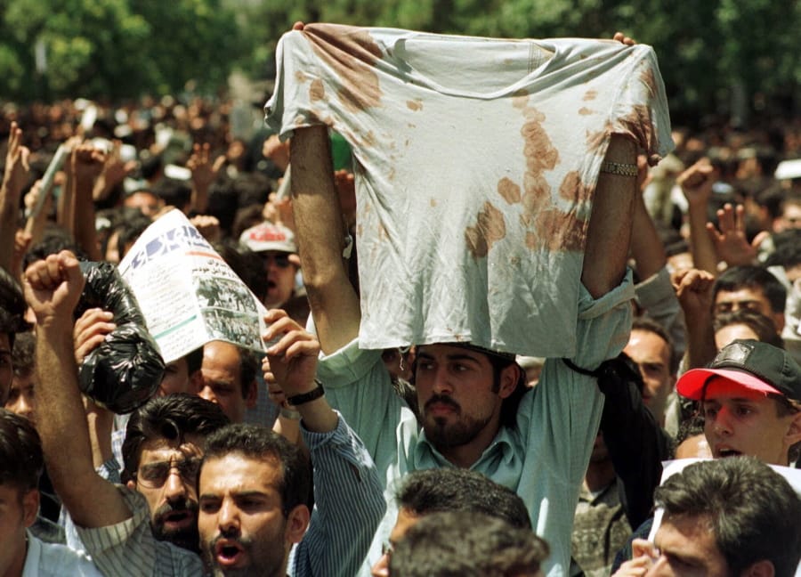 FILE - In this July 12, 1999 file photo, an unidentified student at a rally in Tehran, Iran, holds up the bloody t-shirt of a friend who was injured sometime in the last few days during clashes between police and student demonstrators. The demonstrations that erupted after Iran admitted to accidentally shooting down a Ukrainian jetliner early Wednesday, Jan. 8, 2020, during a tense standoff with the United States, are the latest of several waves of protest going back to the 1979 Islamic Revolution -- all of which have been violently suppressed.