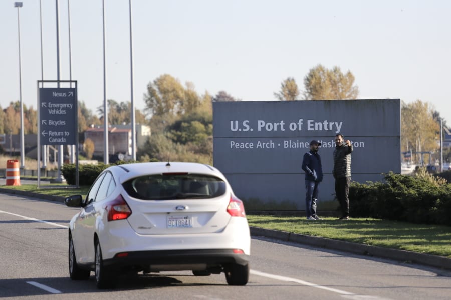 Pedestrians take a photo Oct. 9 at an entry sign as traffic enters the United States from Canada at the Peace Arch Border Crossing in Blaine.