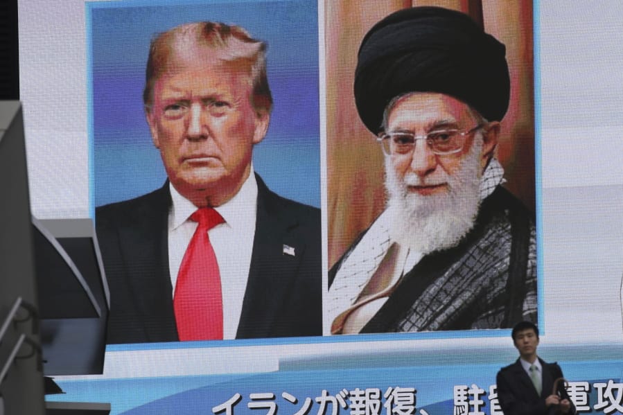 A man walks by a huge screen showing U.S. President Donald Trump, left, and Iranian Supreme Leader Ayatollah Ali Khamenei, in Tokyo, Wednesday, Jan. 8, 2020. Iran struck back at the United States early Wednesday for killing a top Revolutionary Guards commander, firing a series of ballistic missiles at two military bases in Iraq housing American troops in a major escalation between the two longtime foes.