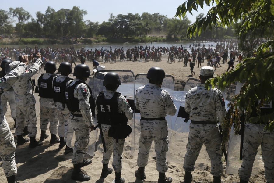 Mexican National Guards stand on the bank of the Suchiate River where Central American migrants are crossing from Guatemala, near Ciudad Hidalgo, Mexico, Monday, Jan. 20, 2020. More than a thousand Central American migrants hoping to reach the United States marooned in Guatemala are walking en masse across a river leading to Mexico in an attempt to convince authorities there to allow them passage through the country.