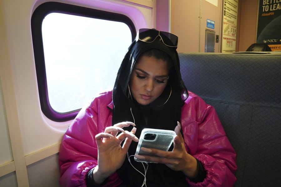 In this Dec. 20, 2019, photo, Amani Al-Khatahtbeh, founder of MuslimGirl.com, sits for an interview inside her family&#039;s video game and electronic store business in Somerville, N.J. Al-Khatahtbeh started the website as a way to defy Muslim stereotypes after 9/11. A decade later, Al-Khatahtbeh has built it into an online magazine with a global audience.