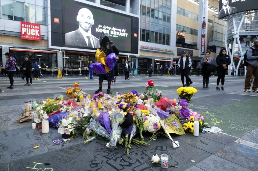 Flowers and candles are placed at a memorial for Kobe Bryant near Staples Center Monday, Jan. 27, 2020, in Los Angeles. Bryant, the 18-time NBA All-Star who won five championships and became one of the greatest basketball players of his generation during a 20-year career with the Los Angeles Lakers, died in a helicopter crash Sunday. (AP Photo/Ringo H.W.