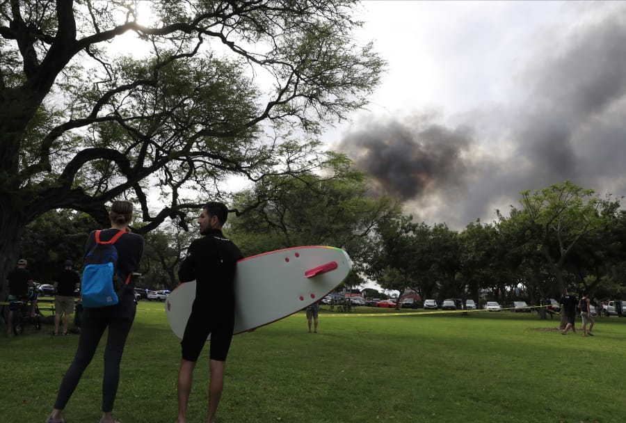 Aina Haina resident Kai Ohashi, right, and Waikiki resident Lucy Taylor observe billowing smoke from a house fire after a shooting and domestic incident at a residence on Hibiscus Road near Diamond Head on Sunday, Jan. 19, 2020, in Honolulu. Witnesses say at least two Honolulu police officers were shot and two civilians were injured. Moments after the shooting, the house was set on fire, possibly by the suspect.