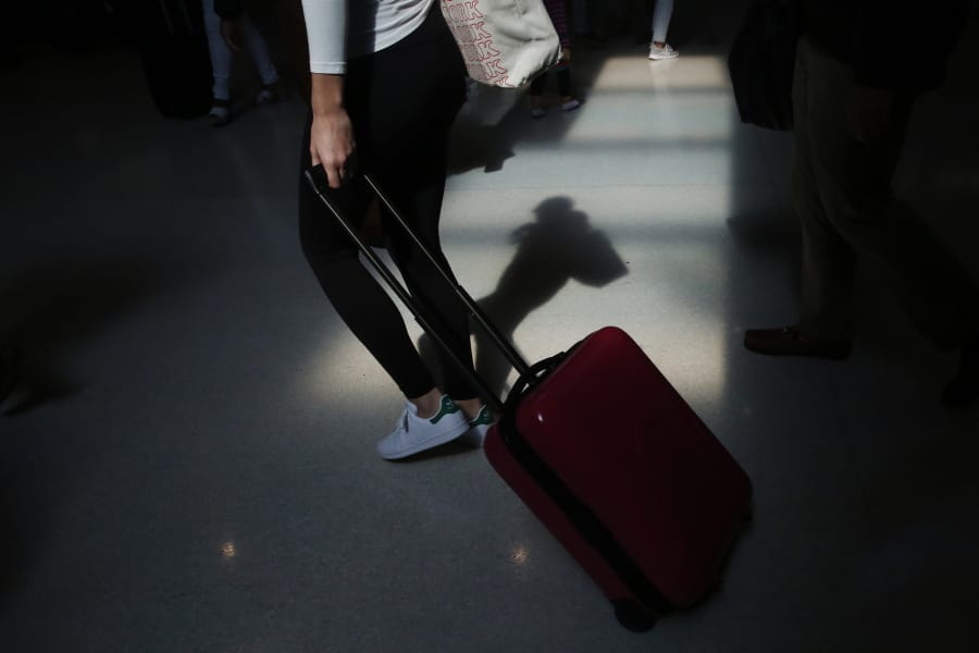 FILE - In this Nov. 27, 2019, file photo a traveler walks through the terminal at the Fort Lauderdale-Hollywood International Airport in Fort Lauderdale, Fla. Summer will be here soon, so it&#039;s a good time to start planning that vacation trip. Experts have plenty of tips for saving money on flights, lodging and other expenses.