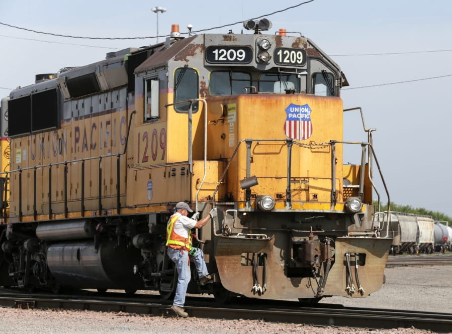 FILE - In this July 20, 2017, file photo, a Union Pacific employee climbs on board a locomotive in a rail yard in Council Bluffs, Iowa. This year&#039;s scheduled completion of a $15 billion automatic railroad braking system will bolster the industry&#039;s argument for eliminating one of the two crew members in most locomotives. But labor groups argue that single-person crews would make trains more accident prone.