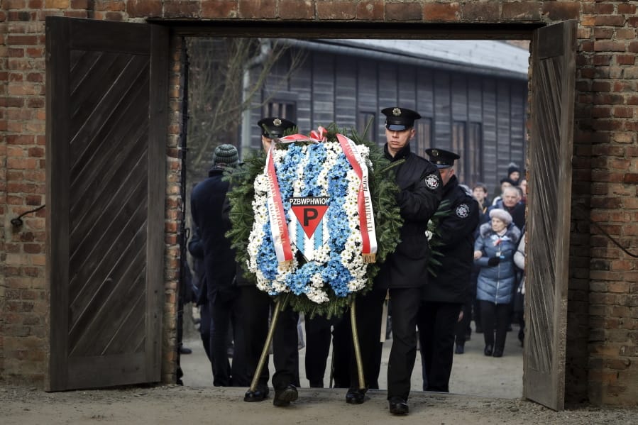 Museum security men carry a wreath at the Auschwitz Nazi death camp in Oswiecim, Poland, Monday, Jan. 27, 2020.
