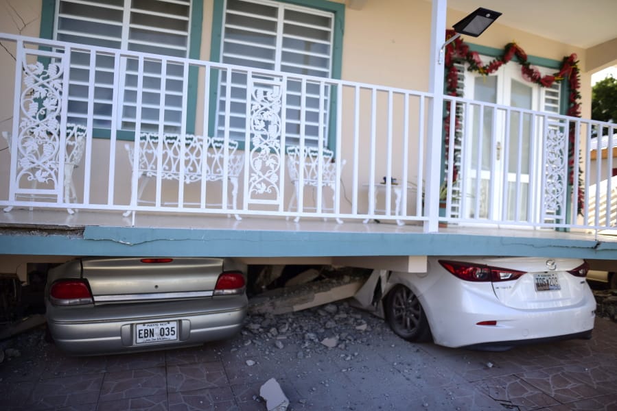 Cars are crushed under a home that collapsed after an earthquake hit Guanica, Puerto Rico, Monday, Jan. 6, 2020. A 5.8-magnitude quake hit Puerto Rico before dawn Monday, unleashing small landslides, causing power outages and severely cracking some homes. There were no immediate reports of casualties.