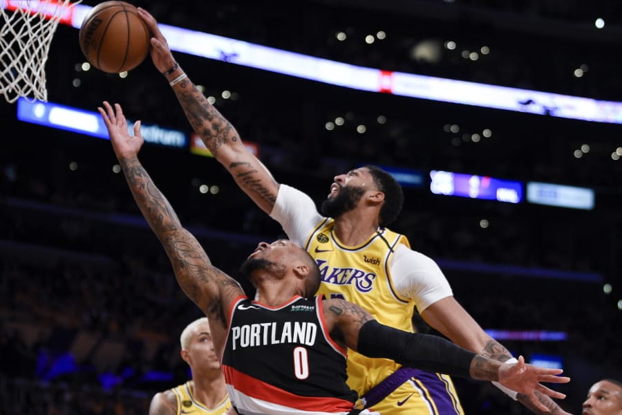 Los Angeles Lakers forward Anthony Davis, top, blocks a shot by Portland Trail Blazers guard Damian Lillard during the first half of an NBA basketball game in Los Angeles, Friday, Jan. 31, 2020.