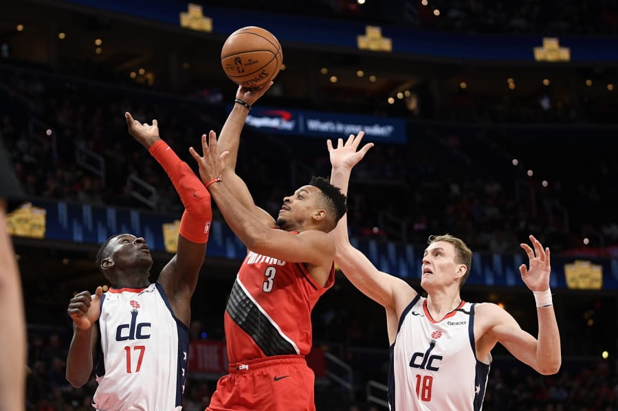 Portland Trail Blazers guard CJ McCollum (3) goes to the basket between Washington Wizards guard Isaac Bonga (17) and center Anzejs Pasecniks (18) during the first half of an NBA basketball game, Friday, Jan. 3, 2020, in Washington.