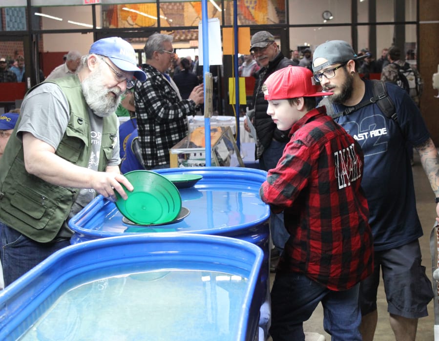 Zachary Castillo, center, watches a demonstration on panning gold as his father looks on. The Pacific Northwest Sportsmen&#039;s Show at the Portland Expo Center in Portland opened on Wednesday and will run through Sunday.