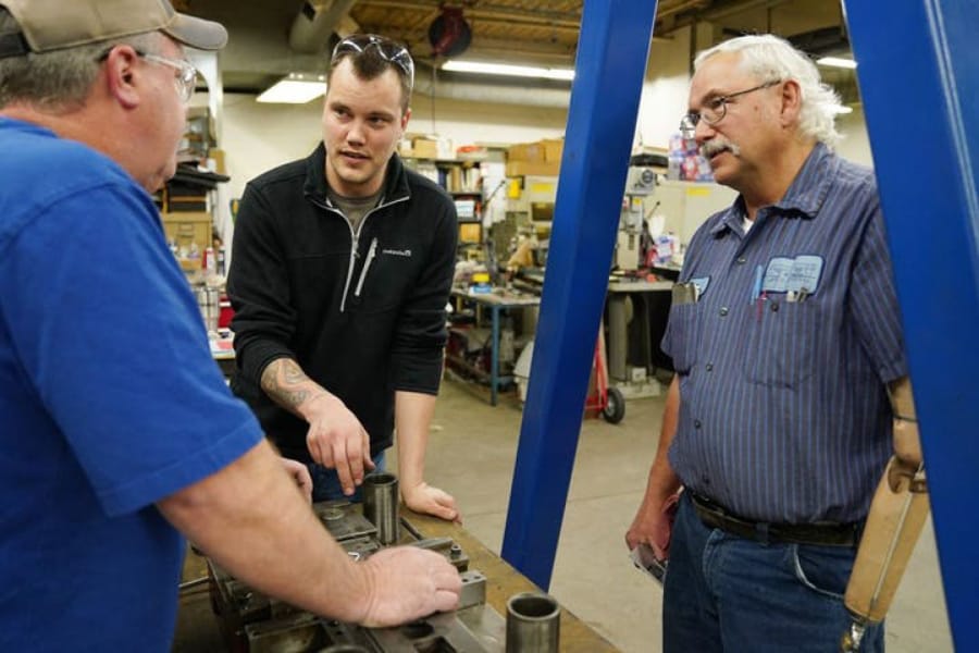 Justin Vandevoort, center, talked with machinist Rod Sammon, left, and press department lead Ben Froman as they worked with a metal stamping die at MRG Tool &amp;amp; Die in Faribault, Minn.