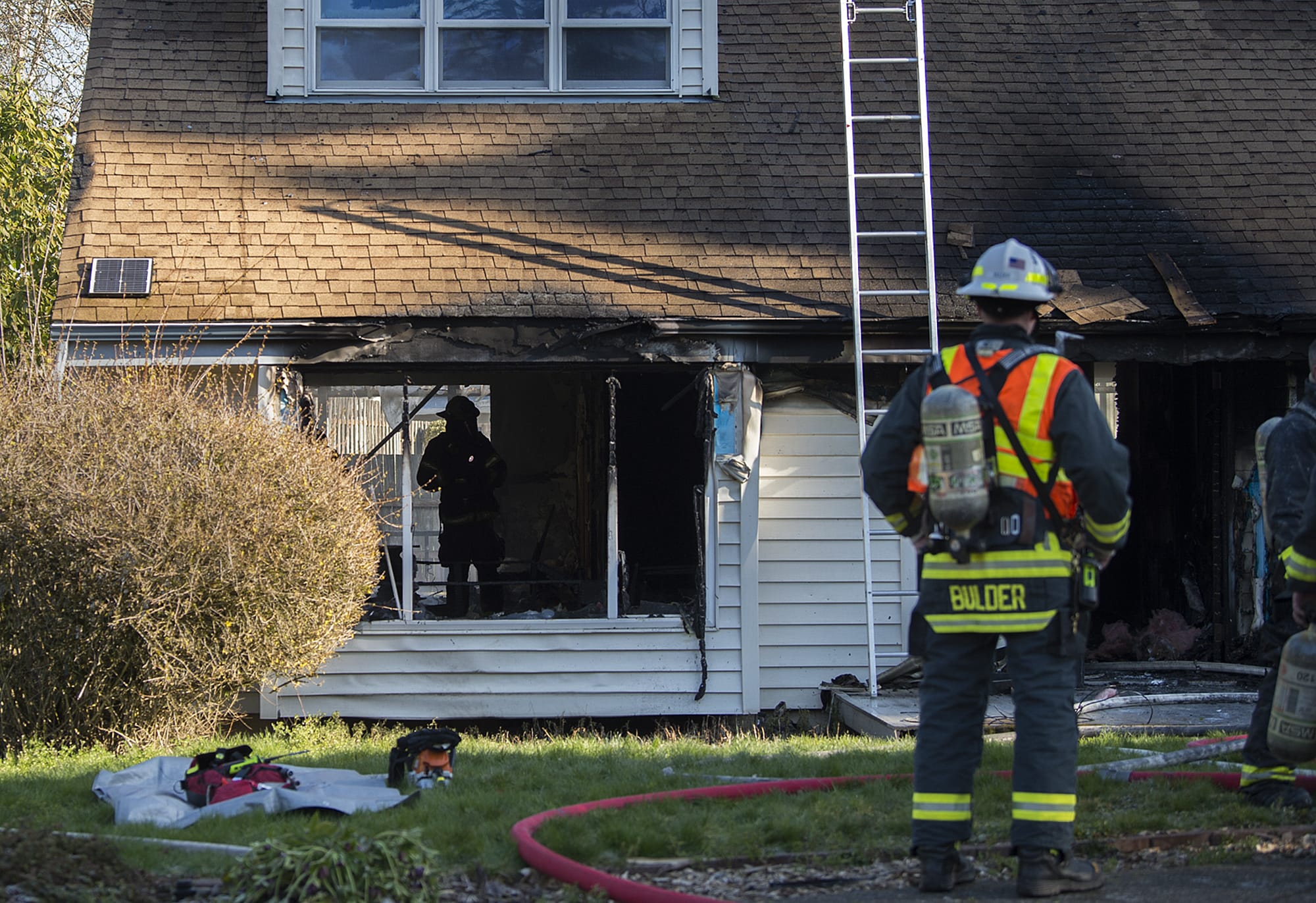 A firefighter, left, uses a flashlight to look over damage to a home in Salmon Creek after a fire gutted the residence on Friday morning, Feb. 21, 2020.