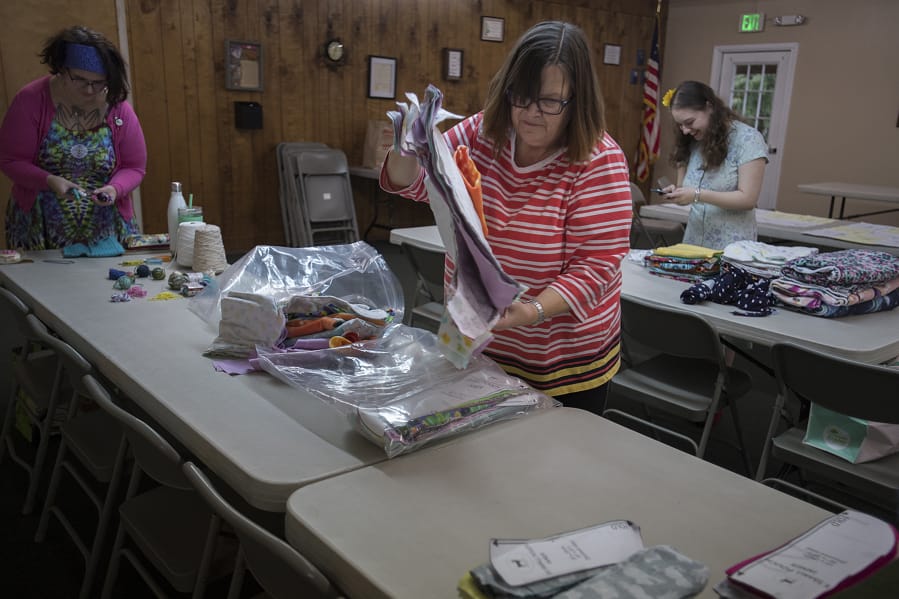 Heather Fisher, from left, of Vancouver joins Lori Moore of Beaverton, Ore., and Sydney Robinson of Vancouver at the Barberton Grange as they prepare for an afternoon of crafting on behalf of animal rescue efforts.