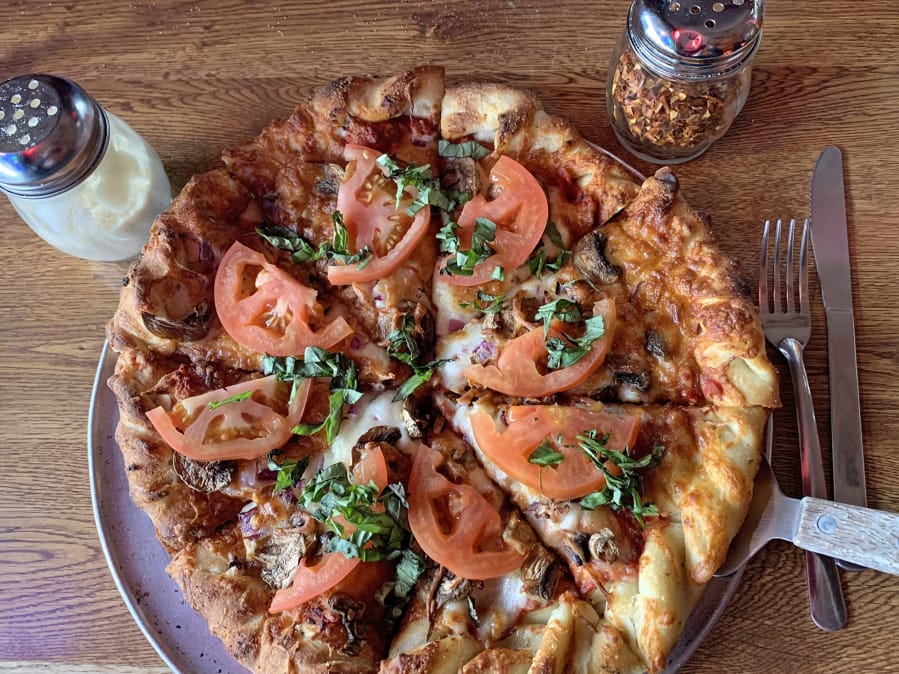 A custom pizza with red onions, mushrooms, fresh tomatoes, and fresh basil at Prairie Bar &amp; Grill.