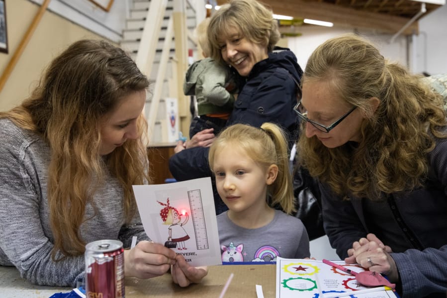 Engineering volunteer Caitlyn Bodda, from left, Agnes Himmelber, 5, Johnny Himmelber, 1, Marian Waggener and Meagan Himmelber, all of Ridgefield, test a circuit made from paper, copper tape and a small battery during Saturday&#039;s Rosie Revere Engineer Day at Pearson Field Education Center.