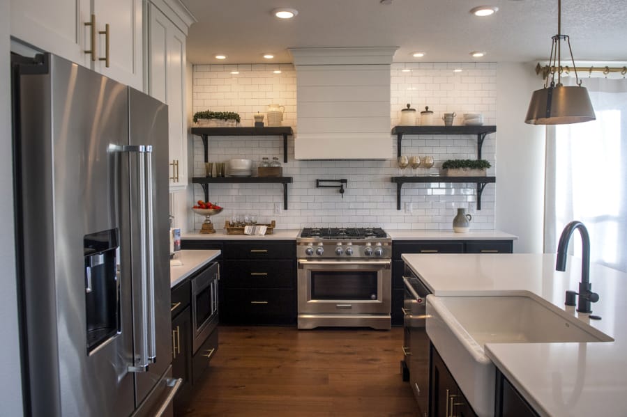 The kitchen in a New Tradition Homes model house at the Velvet Acres development in Vancouver highlights a recent design trend: A move away from all-white kitchens in favor of dark wood or painted cabinets.