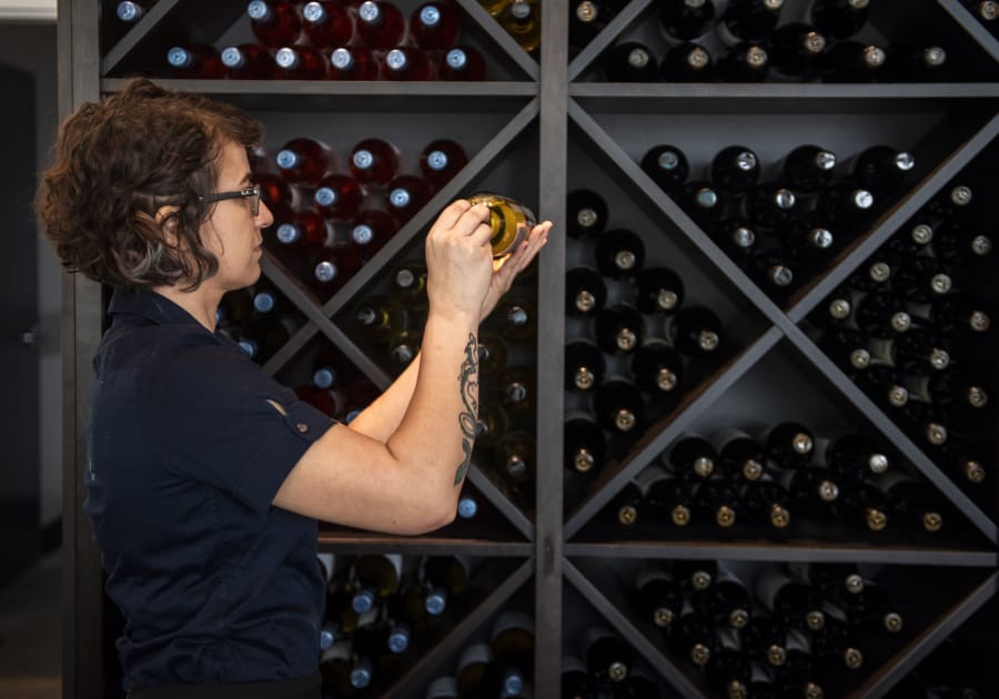 Airfield Estates tasting room assistant manager Audrey Goodine picks out a bottle of wine.