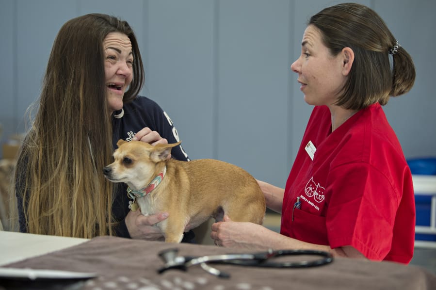 Alysia Meness of Vancouver chats with veterinarian Dr. Lauren Overman as Jalissa, her 7-year-old Chihuahua mix, is examined by a team from the Humane Society for Southwest Washington at the Open House Ministries free pet clinic Thursday in downtown Vancouver.