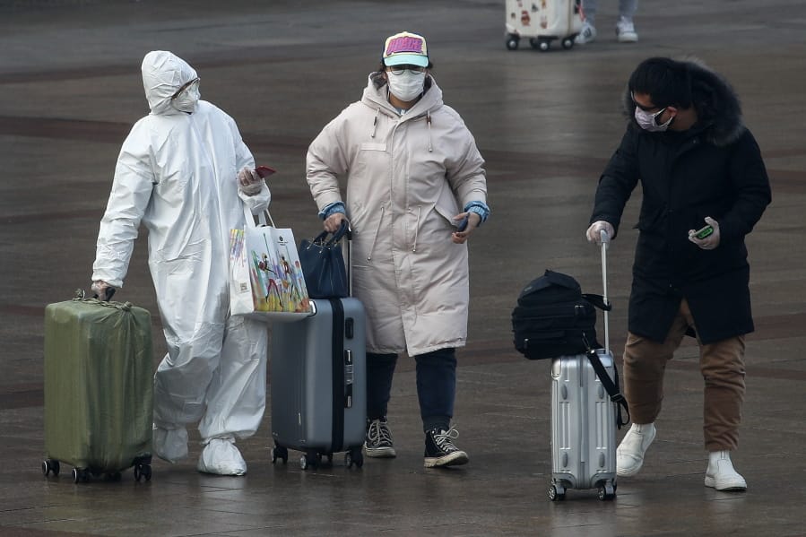 A passenger wearing a full-body protective suit catches the eyes of others as they walk out from the Beijing railway station in Beijing, Tuesday, Feb. 11, 2020. China&#039;s daily death toll from a new virus topped 100 for the first time and pushed the total past 1,000 dead, authorities said Tuesday after leader Xi Jinping visited a health center to rally public morale amid little sign the contagion is abating.
