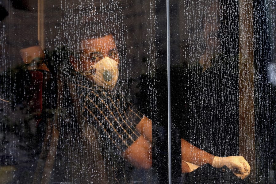 A commuter looks through a water-stained window wearing a mask and gloves to help guard against the Coronavirus, on a public bus in downtown Tehran, Iran, Sunday, Feb. 23, 2020. Iran&#039;s health ministry raised Sunday the death toll from the new virus to 8 people in the country, amid concerns that clusters there, as well as in Italy and South Korea, could signal a serious new stage in its global spread.