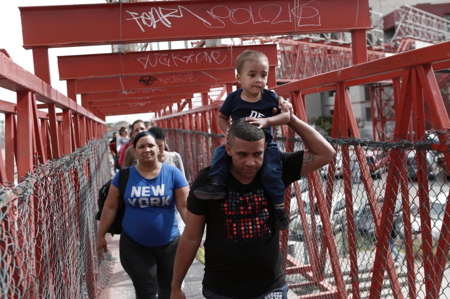 FILE - In this April 29, 2019, file photo, Cuban migrants are escorted in Ciudad Juarez, Mexico, by Mexican immigration officials as they cross the Paso del Norte International bridge to be processed as asylum seekers on the U.S. side of the border.