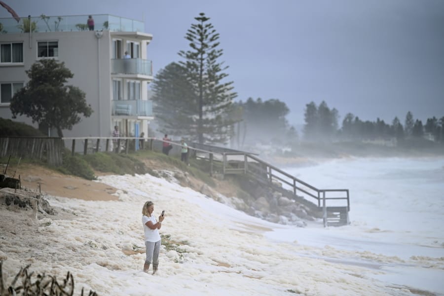 A resident inspects sea foam brought by waves approaching on beach front houses after heavy rain and storms at Collaroy in Sydney&#039;s Northern Beaches, Monday, February 10, 2020. Drought, wildfires and now flooding have given Australia&#039;s weather an almost Biblical feel this year. The good news is that a deluge in eastern parts of the country over recent days has helped dampen deadly fires and ease a crippling drought.