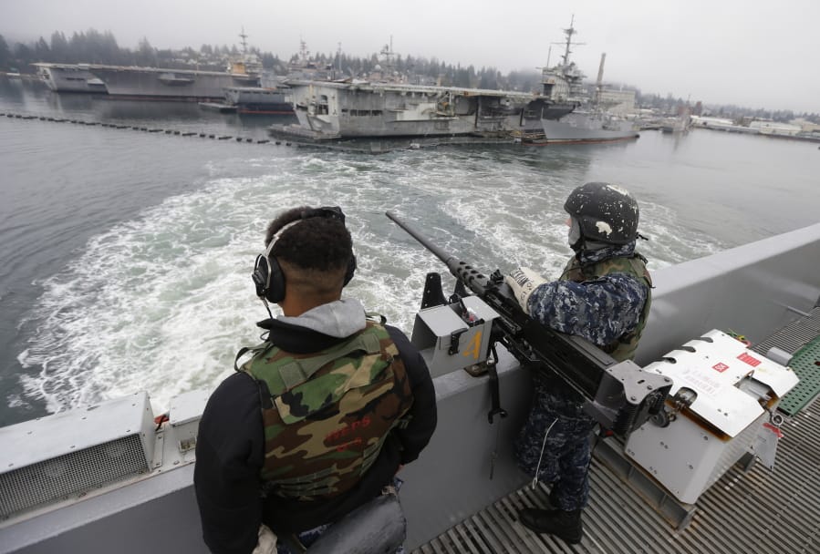 FILE - In this Jan. 13, 2015, file photo, two sailors stand with a gun as the USS John Stennis aircraft carrier leaves Naval Base Kitsap in Washington state. (AP Photo/Ted S.