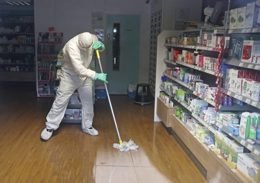 A man in protective clothing cleans the County Oak Medical Centre GP practice which has been temporarily closed &quot;because of an urgent operational health and safety reason&quot;, following reports a member of staff there was one of those infected with coronavirus, in Brighton, England, Monday, Feb. 10, 2020.  Britain has declared the new coronavirus that emerged from China a &quot;serious and imminent threat to public health&#039;&#039; and announced new measures Monday to combat the spread of the disease.