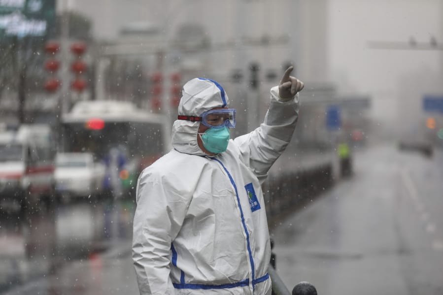 A worker wearing a protective suit gestures to a driver outside a tumor hospital newly designated to treat COVID-19 patients in Wuhan in central China&#039;s Hubei Province, Saturday, Feb. 15, 2020. The virus is thought to have infected more than 67,000 people globally and has killed at least 1,526 people, the vast majority in China, as the Chinese government announced new anti-disease measures while businesses reopen following sweeping controls that have idled much of the economy.