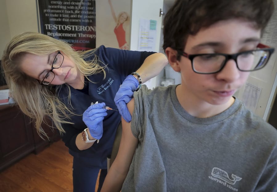 FILE - In this Jan. 3, 2019, file photo, Wendy Kerley gives Ethan Getman, 15, a shot of the flu vaccine at the Cordova Shot Nurse clinic in Memphis, Tenn. A second wave of flu is hitting the U.S., turning this into one of the nastiest flu seasons for children in a decade.
