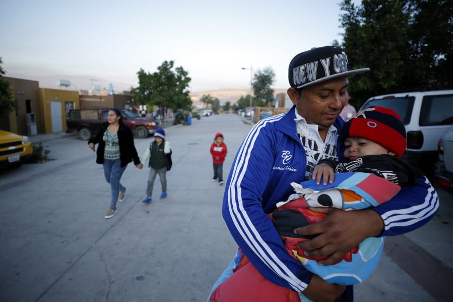 Juan Carlos Perla carries his youngest son, Joshua Mateo Perla, as the family leaves their home July 10, 2019, in Tijuana, Mexico, for an asylum hearing in San Diego.