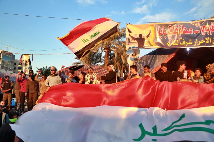 Anti-government protesters chant slogans while holding the national flags during a demonstration against the newly appointed Prime Minister Mohammed Allawi in Tahrir Square, Baghdad, Iraq, Monday, Feb. 3, 2020.