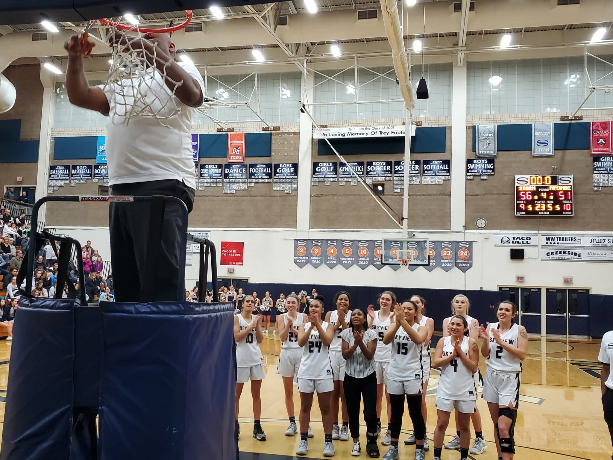Skyview coach Brett Johnson cuts the net as the Skyview players applaud after the Storm beat Camas 56-51 to clinch the 4A Greater St.
