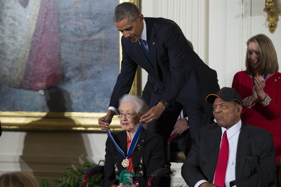 FILE - In this Nov. 24, 2015 photo, Willie Mays, right, looks on as President Barack Obama presents the Presidential Medal of Freedom to NASA mathematician Katherine Johnson during a ceremony in the East Room of the White House, in Washington. Johnson, a mathematician on early space missions who was portrayed in film &quot;Hidden Figures,&quot; about pioneering black female aerospace workers, died Monday, Feb. 24, 2020.