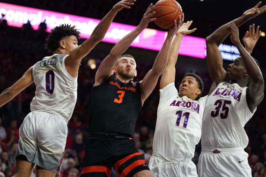 Oregon State forward Tres Tinkle (3) drives between Arizona guard Josh Green (0), Ira Lee (11), and Christian Koloko (35) during the first half of an NCAA college basketball game Thursday, Feb. 20, 2020, in Tucson, Ariz.