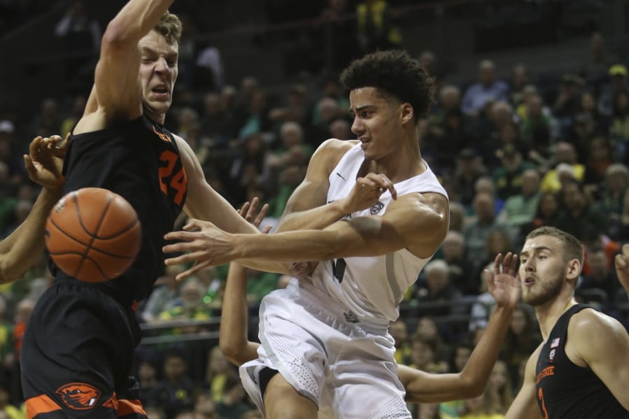 Oregon&#039;s Will Richardson, center, passes the ball between Oregon State&#039;s Kylor Kelley, left, and Tres Tinkle, right, during the first half of an NCAA college basketball game in Eugene, Ore., Thursday, Feb. 27, 2020.
