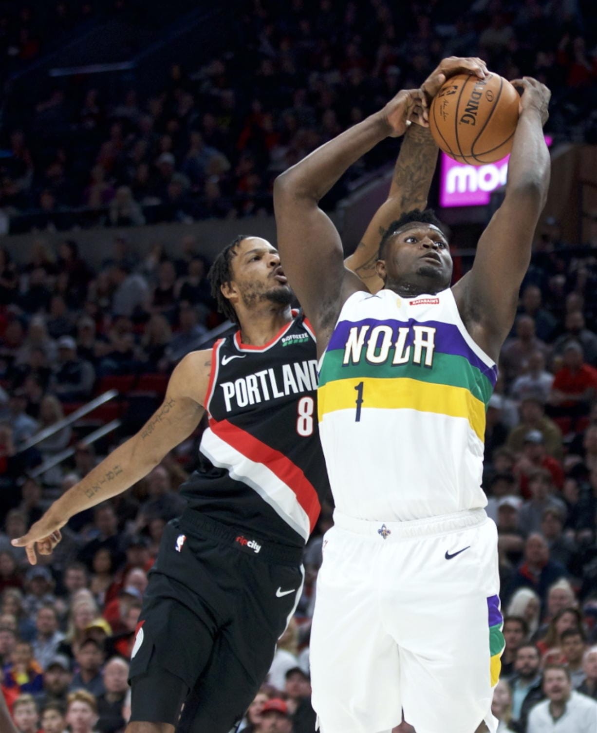 New Orleans Pelicans forward Zion Williamson, right, shoots and scores despite the defense of Portland Trail Blazers forward Trevor Ariza during the first half of an NBA basketball game in Portland, Ore., Friday, Feb. 21, 2020.