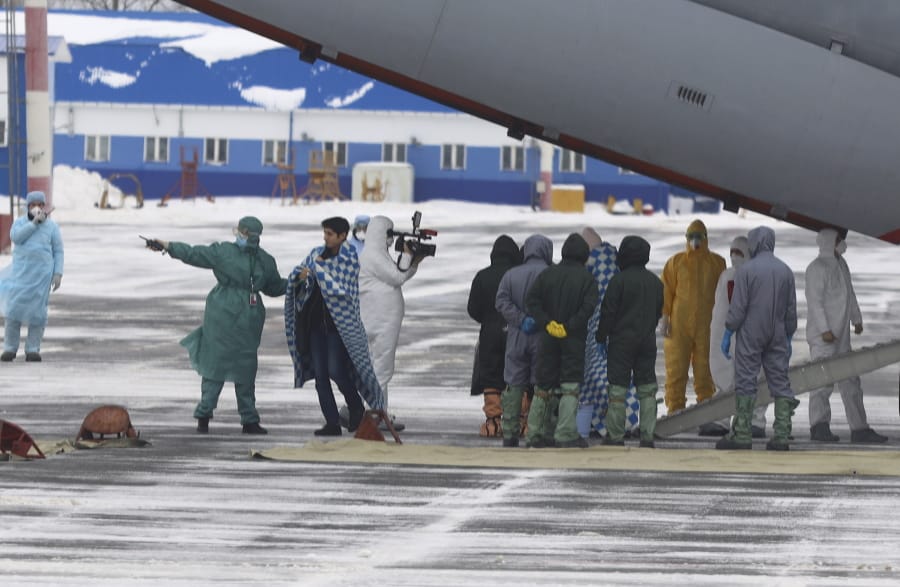 A group of medical personnel meet people, carried by a Russian military plane at an airport outside Tyumen, Russia, Wednesday, Feb. 5, 2020. Russia has evacuated 144 people, Russians and nationals of Belarus, Ukraine and Armenia, from the epicenter of the coronavirus outbreak in Wuhan, China, on Wednesday.