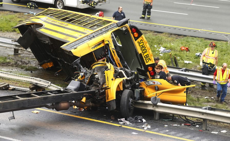 FILE - In this May 17, 2018 file photo, emergency personnel examine a school bus after it collided with a dump truck, injuring multiple people, on Interstate 80 in Mount Olive, N.J. A teacher and student were killed and dozens of other children injured after the bus, crossing multiple lanes, was hit by a dump truck from behind and pushed off its frame. The bus driver, Hudy Muldrow, who pleaded guilty in December 2019 to reckless vehicular homicide, assault by auto and child endangerment, faces sentencing Wednesday, Feb. 26, 2020.