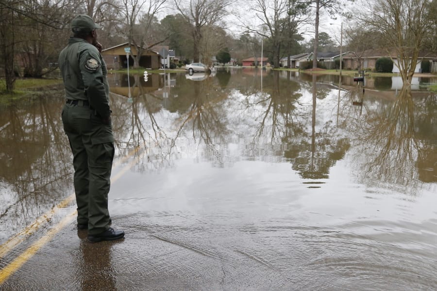 A Mississippi Department of Wildlife, Fisheries and Parks lawman, observes the swirling Pearl River floodwaters drain from North Canton Club Circle in Jackson, Miss., Tuesday afternoon, Feb. 18, 2020. Officials have limited entry to the flooded neighborhoods as they have warned residents about the contamination of the receding waters and the swift currents. (AP Photo/Rogelio V.