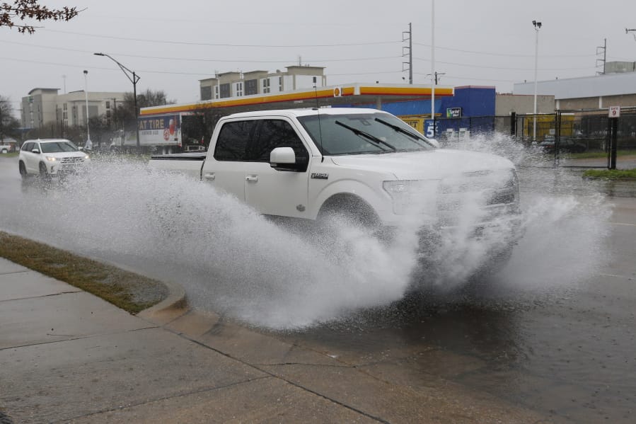 A vehicle sprays water as rain falls in downtown Jackson, Miss., Tuesday, Feb. 11, 2020, making for cascades of splashed water as traffic drives through. The National Weather Service says minor to moderate flooding is expected from central Mississippi to north Georgia following downpours. (AP Photo/Rogelio V.